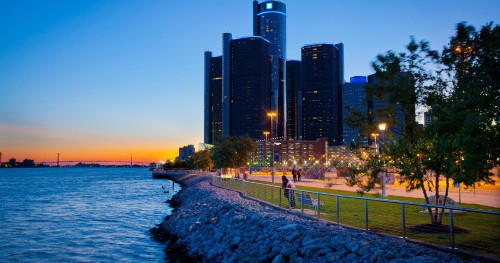 Image people walking on sidewalk near body of water during sunset