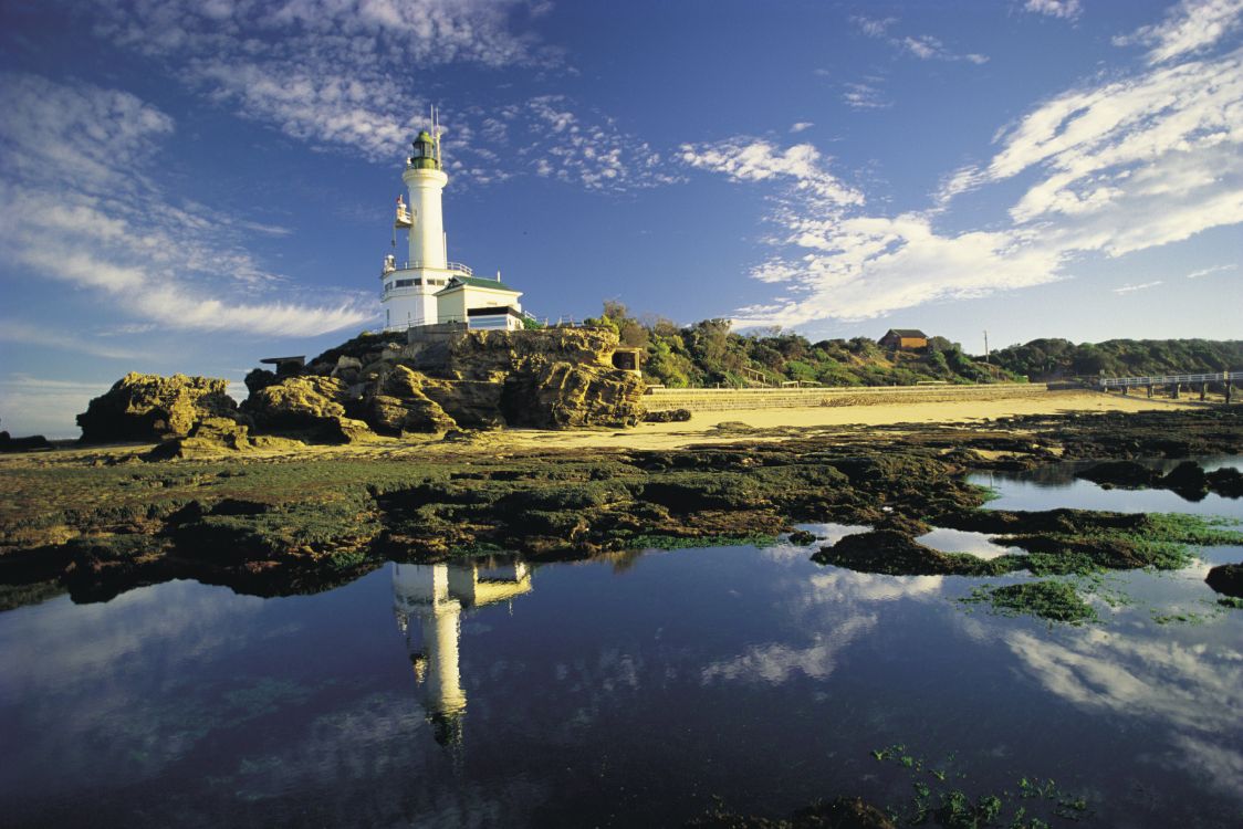 white lighthouse near body of water under blue sky during daytime