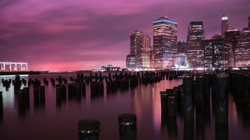 Image city skyline across body of water during night time