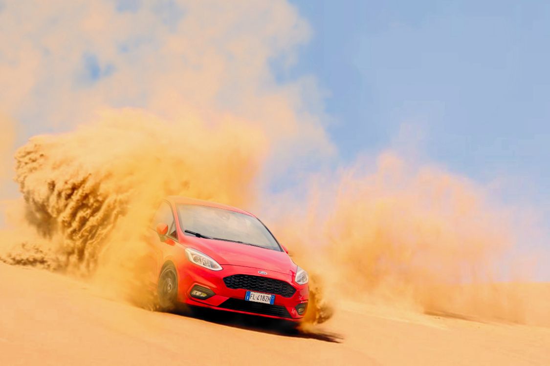 red car on brown sand under white clouds and blue sky during daytime