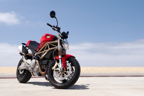 Image red and black motorcycle on gray sand during daytime