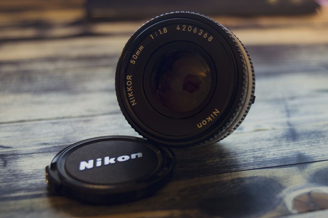Schwarzes Nikon-Kameraobjektiv Auf Braunem Holztisch. Wallpaper in 2512x1670 Resolution