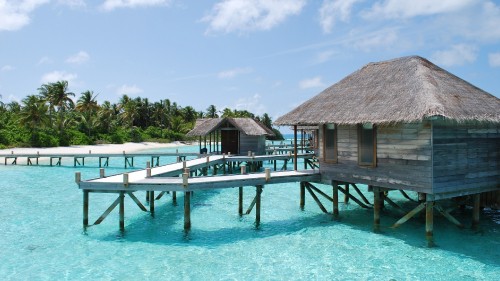 Image brown wooden house on blue sea under blue sky during daytime