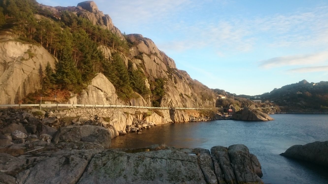 brown rocky mountain beside body of water during daytime