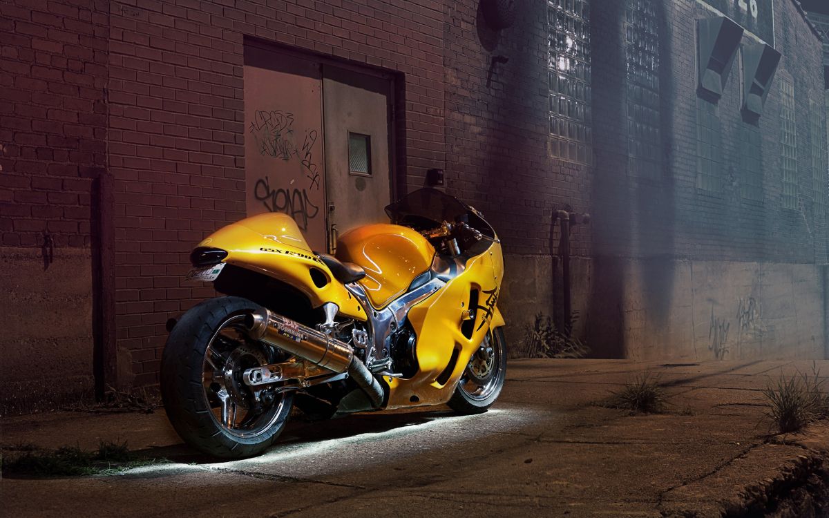 yellow and black sports bike parked beside brown brick wall