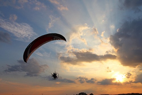 Image person in parachute under cloudy sky during daytime