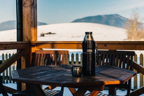 Image black vacuum flask on brown wooden table