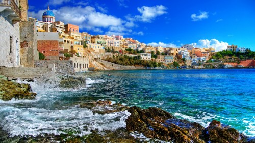 Image brown and white concrete buildings beside body of water under blue sky during daytime