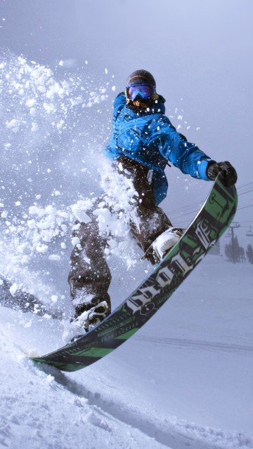 Image man in blue jacket riding on snowboard during daytime