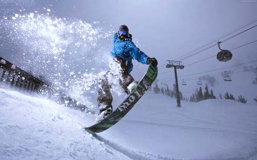 Image man in blue jacket riding on snowboard during daytime