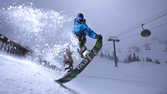 Image man in blue jacket riding on snowboard during daytime