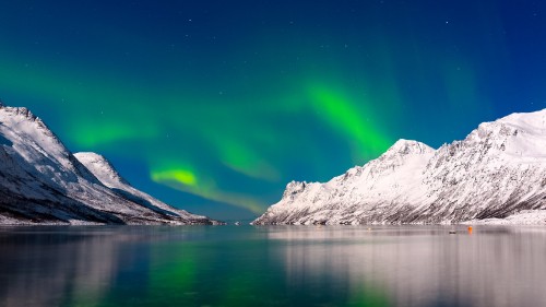 Image snow covered mountain beside body of water during daytime