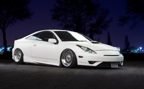 Image white porsche 911 parked on black asphalt road during night time