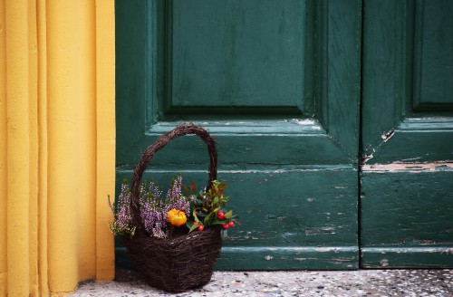 Image brown wicker basket with green leaves on gray concrete floor