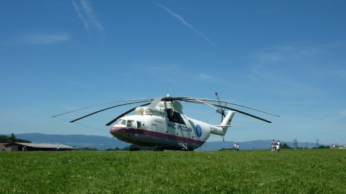 Image white and red helicopter on green grass field under blue sky during daytime