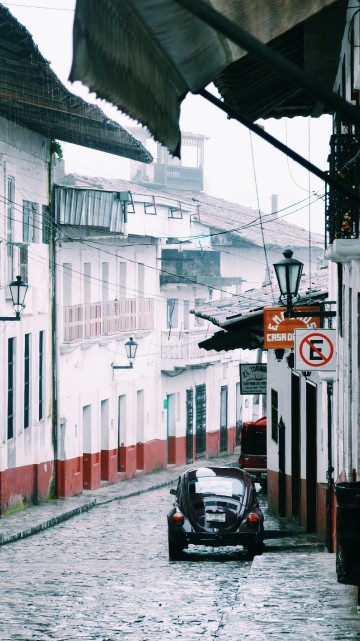 Image black motor scooter parked beside white and red building during daytime