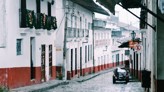 Image black motor scooter parked beside white and red building during daytime