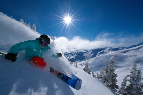 Image person in red jacket and blue pants riding on snowboard during daytime