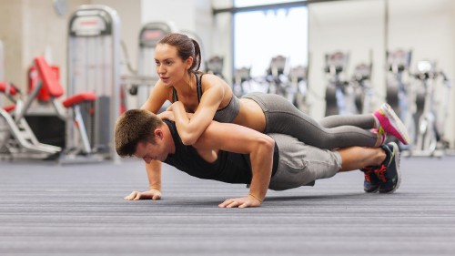 Image woman in black tank top and gray sweatpants doing push up