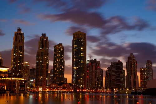 Image city skyline across body of water during night time