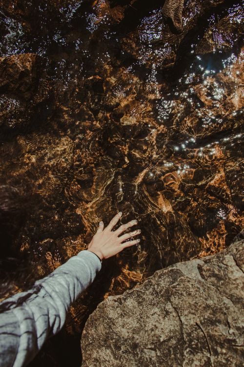 person in gray long sleeve shirt standing on brown rock