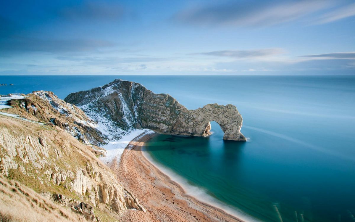 Brauner Felsiger Berg Neben Blauem Meer Unter Blauem Himmel Tagsüber. Wallpaper in 1920x1200 Resolution