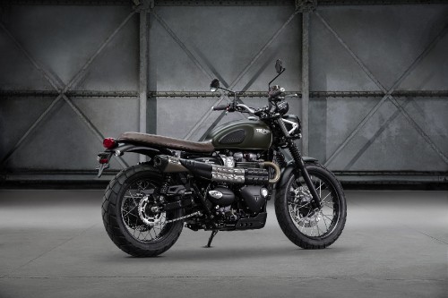 Image black and orange motorcycle parked beside gray wall