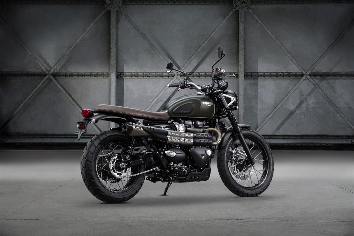 black and orange motorcycle parked beside gray wall