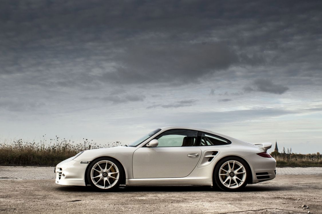 white porsche 911 on gray asphalt road under gray cloudy sky