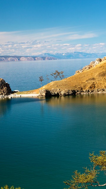 Image blue lake surrounded by brown and green mountains under blue sky during daytime