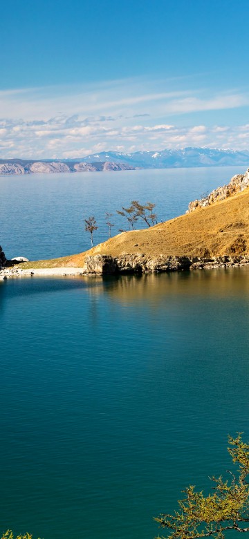 Image blue lake surrounded by brown and green mountains under blue sky during daytime