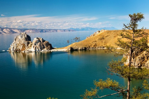 Image blue lake surrounded by brown and green mountains under blue sky during daytime