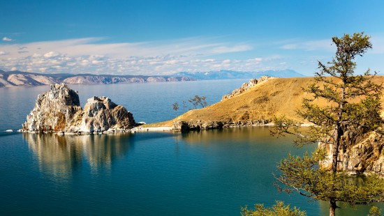 Image blue lake surrounded by brown and green mountains under blue sky during daytime