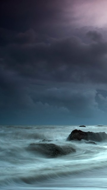 Image ocean waves crashing on rocks under cloudy sky