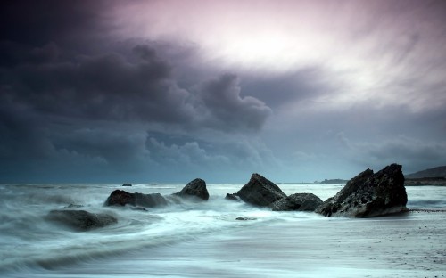 Image ocean waves crashing on rocks under cloudy sky