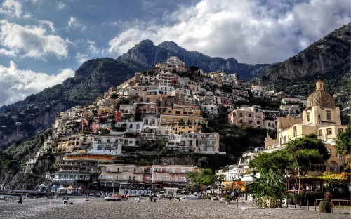 Image white and brown concrete buildings near mountain under white clouds during daytime