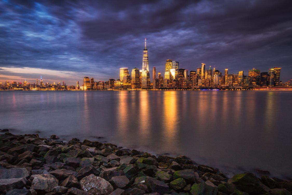 city skyline across body of water during night time