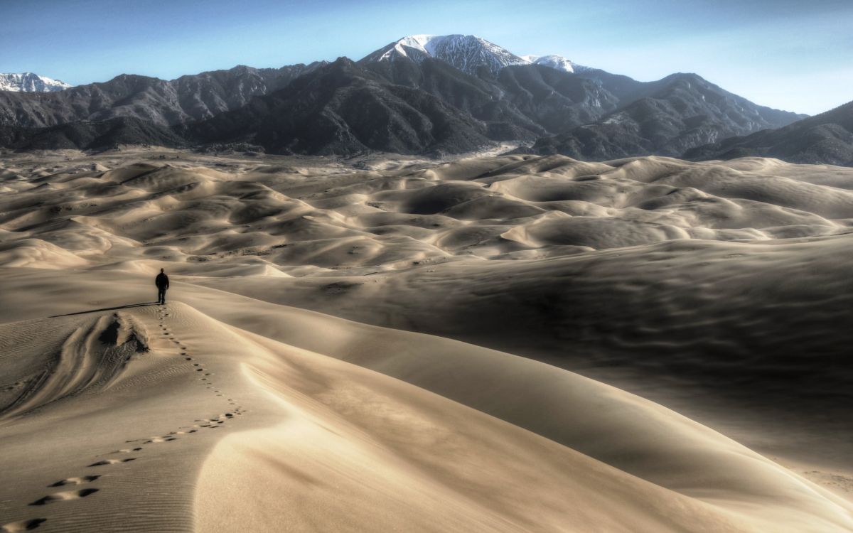 brown sand with snow covered mountain in distance