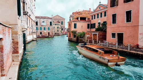 Image white and brown boat on water near concrete buildings during daytime