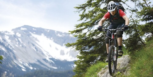 Image man in black shirt riding black mountain bike on green grass field during daytime