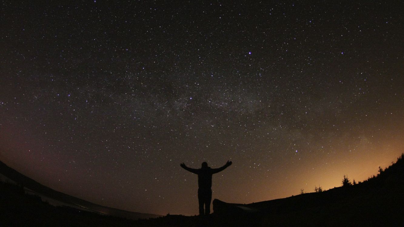 Silhouette of Person Standing on Hill Under Starry Night. Wallpaper in 2048x1152 Resolution