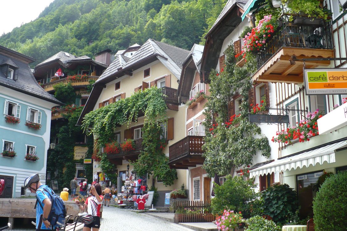 Personas Sentadas en un Banco Cerca Del Edificio de Hormigón Marrón y Blanco Durante el Día. Wallpaper in 3072x2048 Resolution