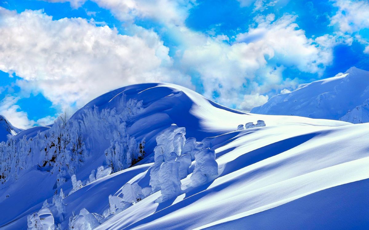 snow covered mountain under white clouds and blue sky during daytime