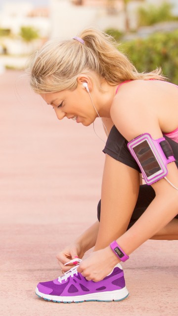 Image woman in pink tank top and purple nike athletic shoes sitting on brown wooden floor during