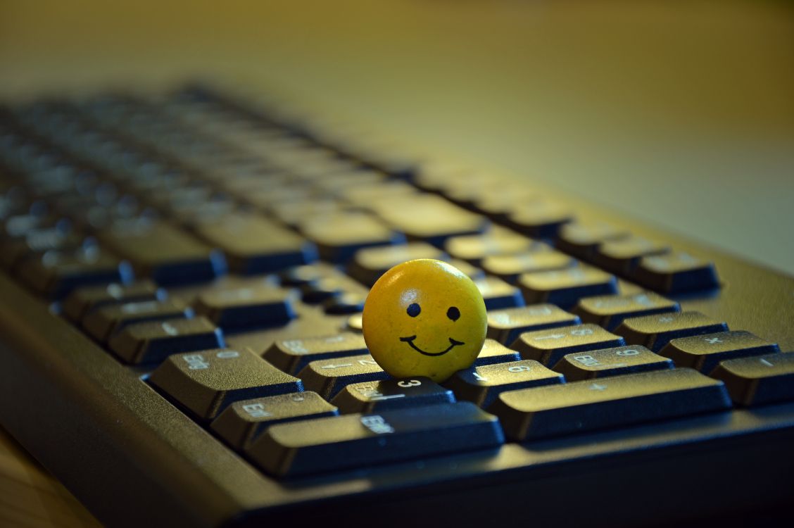 Gelber Smiley-Ball Auf Schwarzer Computertastatur. Wallpaper in 6016x4000 Resolution
