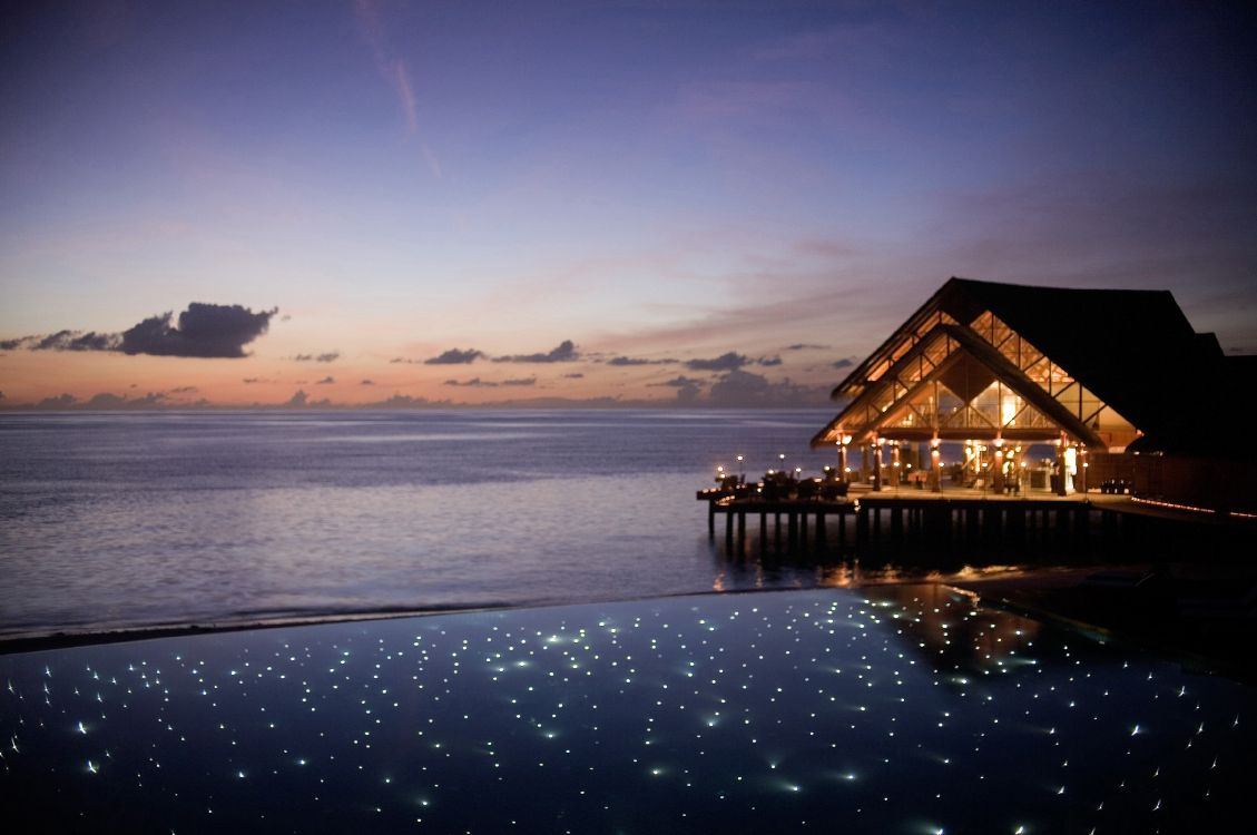 brown wooden house on body of water during sunset