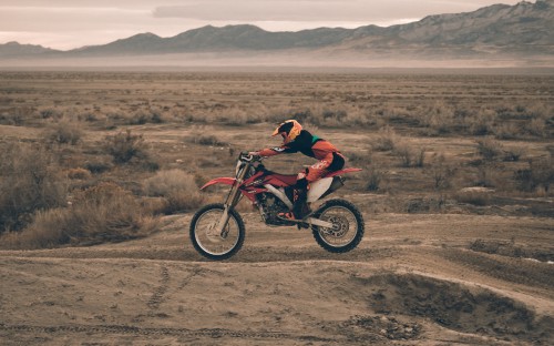 Image man in red jacket riding on motocross dirt bike