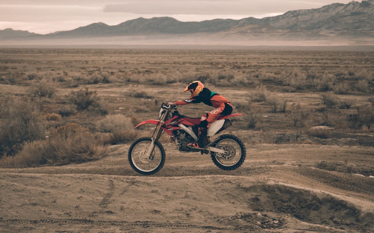 man in red jacket riding on motocross dirt bike