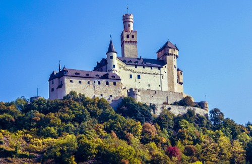 Image white and gray concrete castle on top of green mountain during daytime