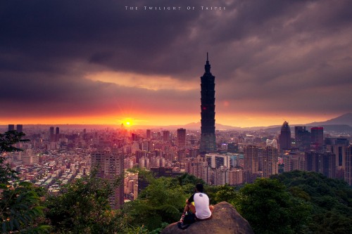 Image man in white shirt sitting on rock during sunset